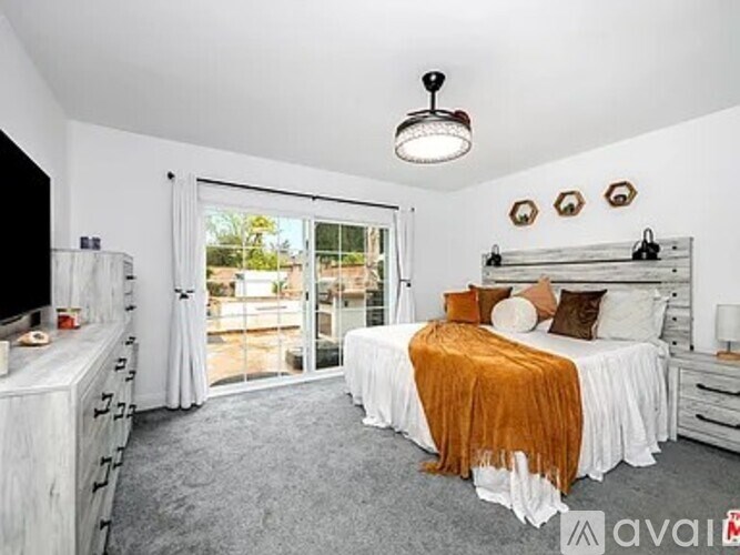A bedroom with a large bed and a sliding glass door leading to a balcony.