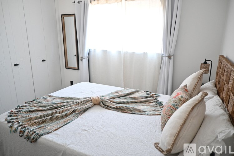 A bed with a white comforter and a decorative pillow is in the image.