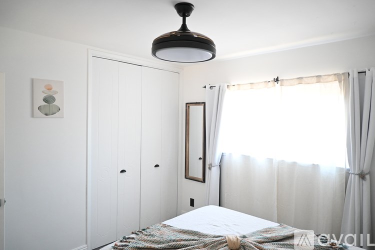 A bedroom with a bed, a dresser, and a window with curtains.
