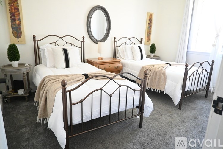 Three beds with white bedding and a round mirror on the wall.