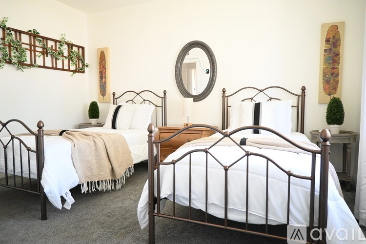 Two beds in a room with a mirror and a wall hanging.