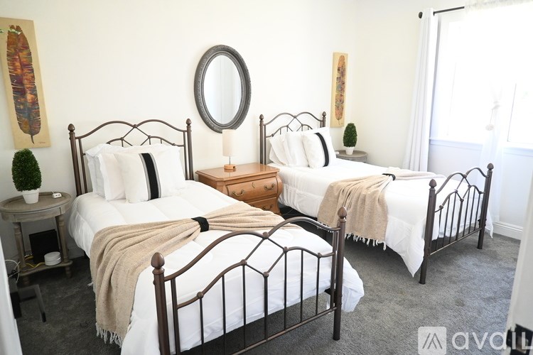 A bedroom with two beds and a round mirror on the wall.