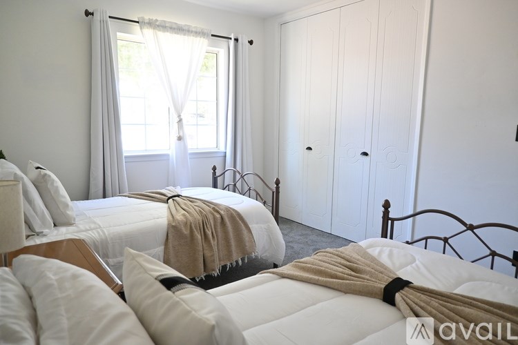 A bedroom with a bed, a window with curtains, and a wardrobe.