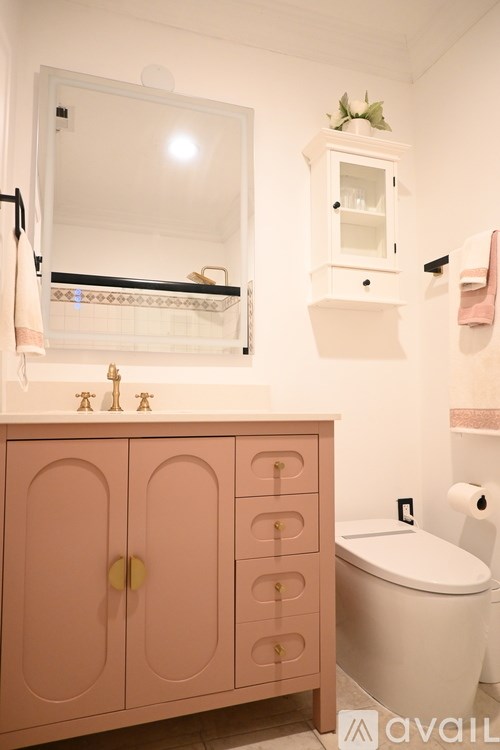 A bathroom with a pink cabinet and a white toilet.