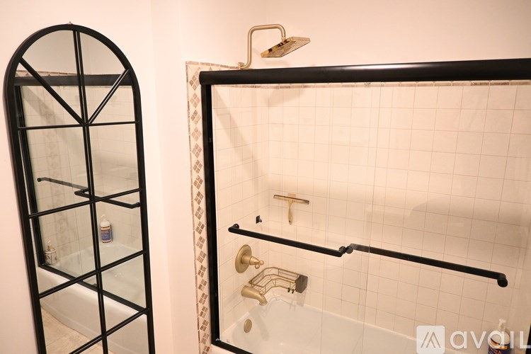 A black framed shower with a glass door and a gold shower head.