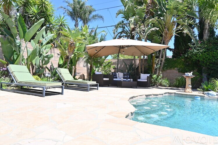 A pool with a white umbrella and two lounge chairs.