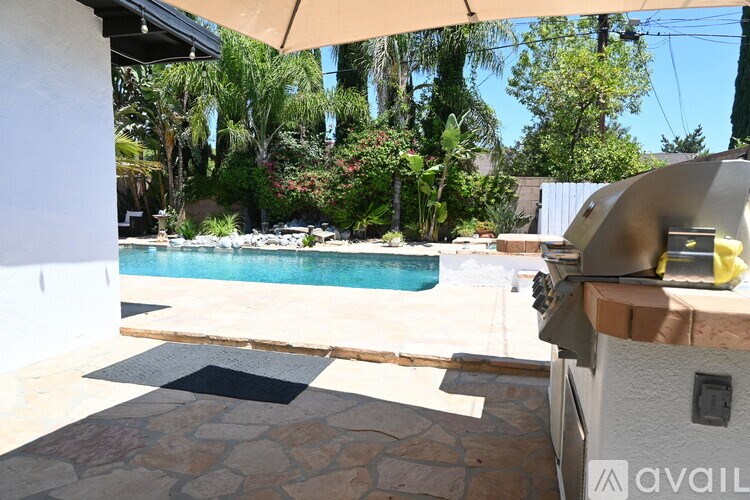 A pool area with a stone patio and a white building.