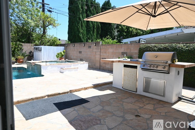 A patio with a grill and a pool.