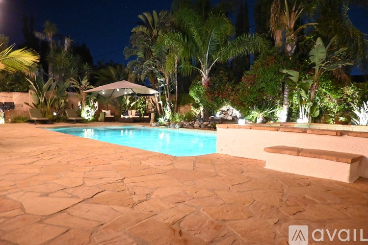A pool surrounded by palm trees at night.