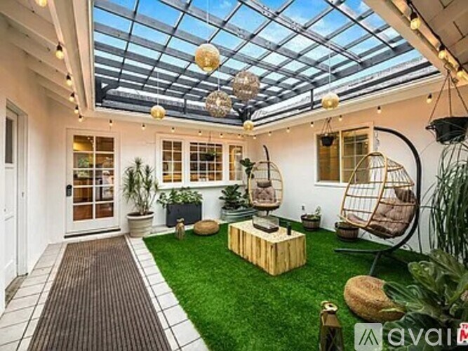 A patio with a glass roof, a hanging chair, and a wooden bench.