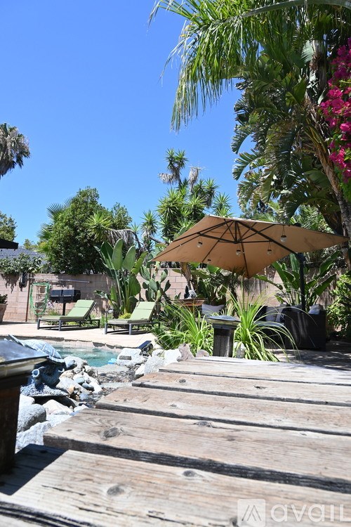 A wooden deck with a hot tub and a large umbrella.
