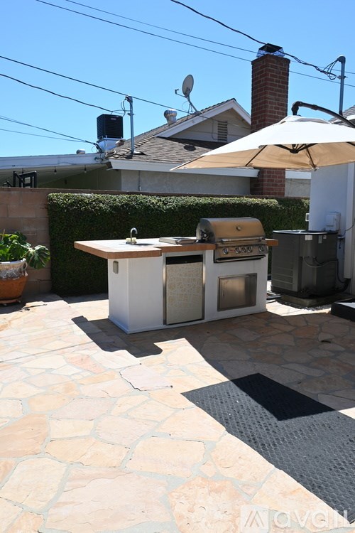A patio with a grill and an umbrella.