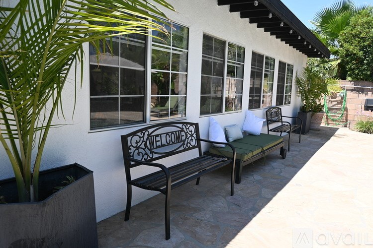 A black bench with a welcome sign sits on a patio.