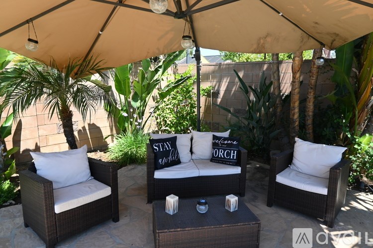 A patio with a couch, chairs and a sign that says "Stay a While".