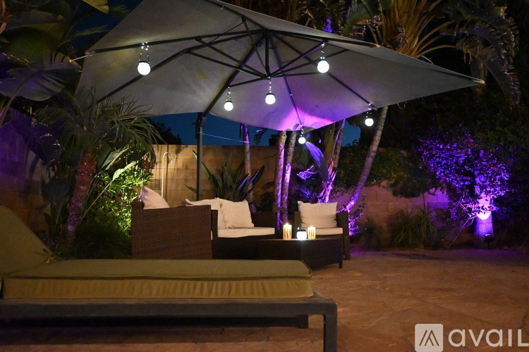 A patio with a white umbrella and a couch under it.