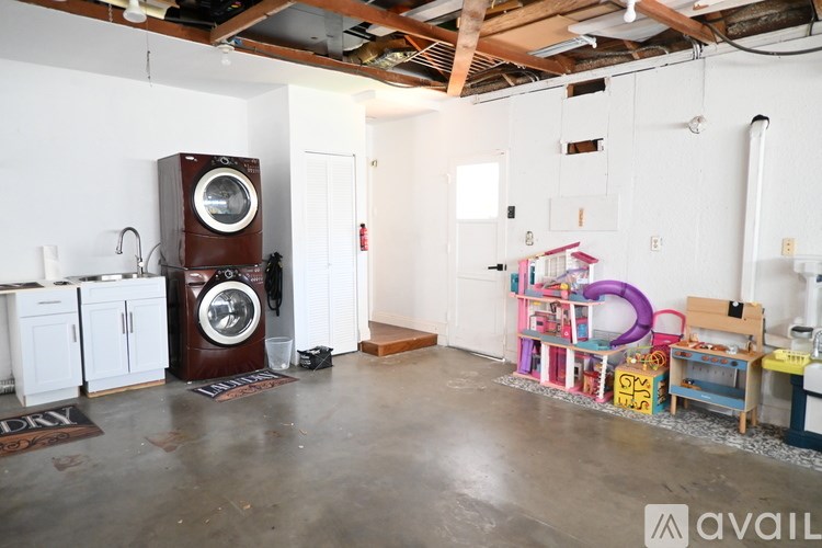 A room with a washing machine on top of a cabinet and a child's play area with toys.