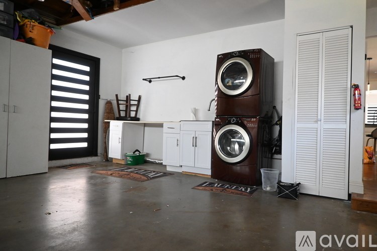 A room with a washing machine and a dryer on top of it.