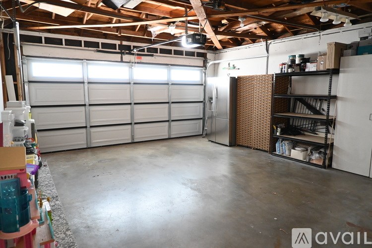 A large open garage with a white door and a brown shelving unit.