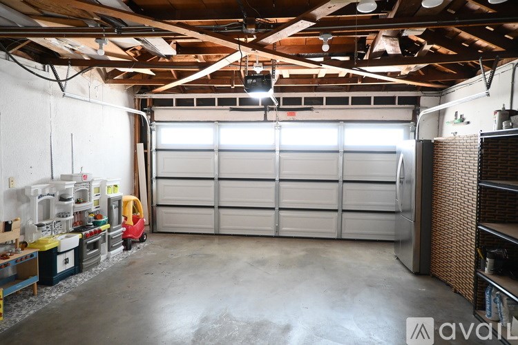 A large garage with a red toy car and a white wall.