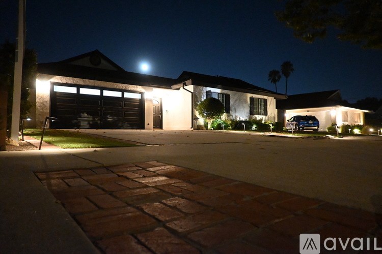 A house with a driveway and garage is lit up at night.