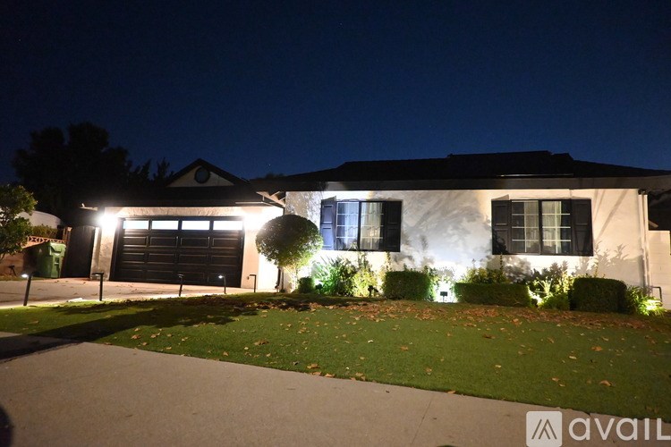 A house with a lit up driveway at night.