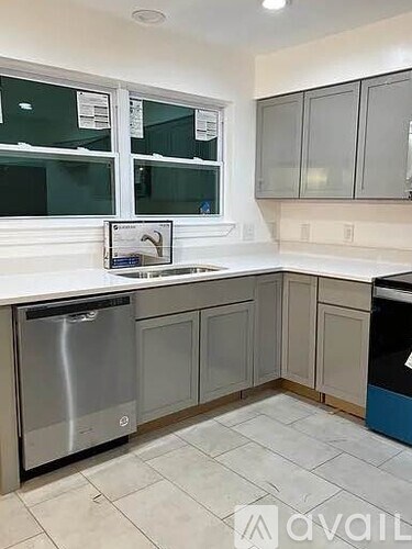 A kitchen with a stainless steel dishwasher and a white countertop.