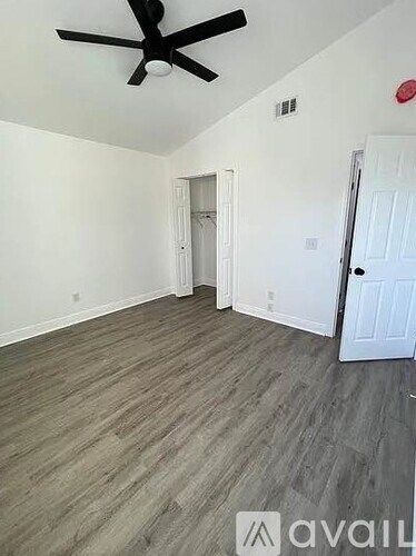 A room with a ceiling fan and wood flooring.