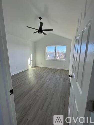 A room with a ceiling fan and wooden flooring.