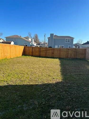 A backyard with a wooden fence and a grassy area.