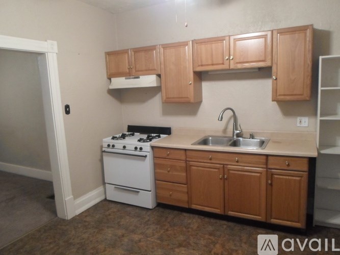 A kitchen with a white stove and wooden cabinets.