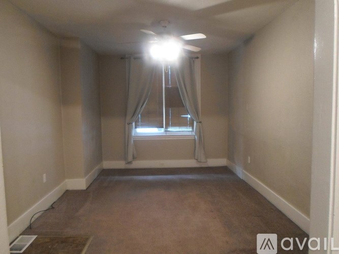 A room with a window and curtains is available for rent.