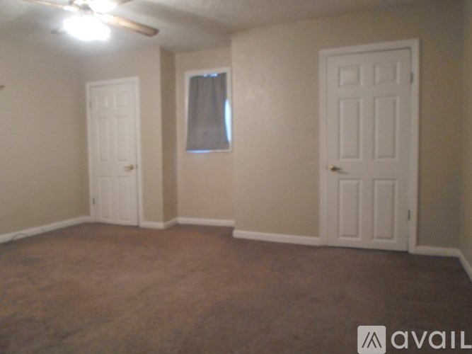 A room with a ceiling fan and two doors.