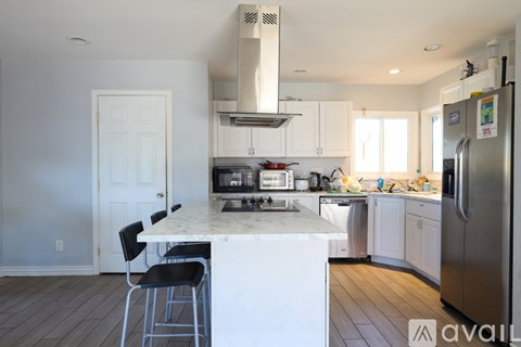 A kitchen with white cabinets and a marble island.