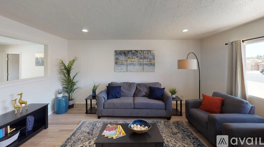 A living room with a grey couch, a black coffee table, and a painting on the wall.