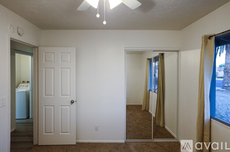 A room with a door, a window with curtains, and a ceiling fan.