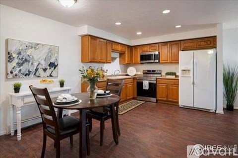 A dining room with a table set for two and a kitchen in the background.