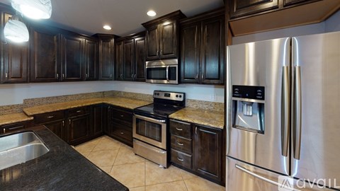 A modern kitchen with dark wood cabinets and stainless steel appliances.