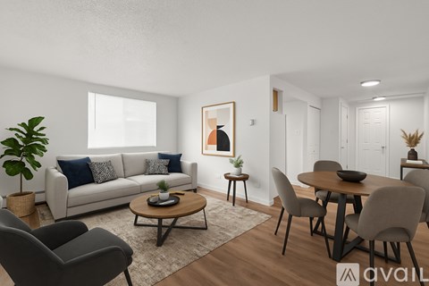 A living room with a grey couch, a wooden coffee table, and a dining table with grey chairs.