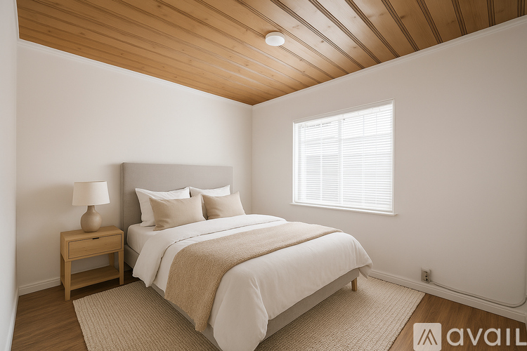 A bedroom with a bed, nightstand, and window.