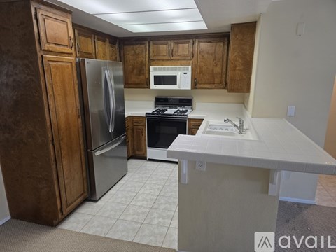 A kitchen with a refrigerator, microwave, oven, and sink.