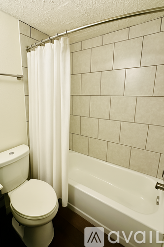 A white toilet sits next to a bathtub in a bathroom.