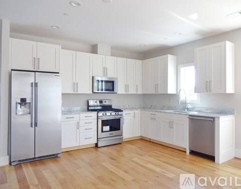 A kitchen with white cabinets and a wooden floor.