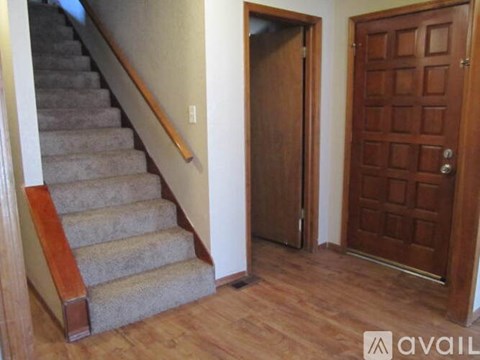A room with a staircase, a door and a wall.