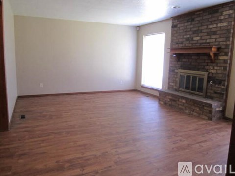 A room with wooden floors and a brick fireplace.