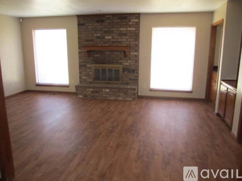 A room with a brick fireplace and wooden floors.