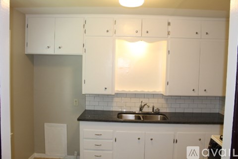 A kitchen with white cabinets and a black countertop.