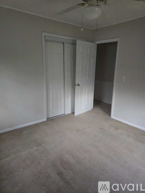 A room with two white doors and a ceiling fan.