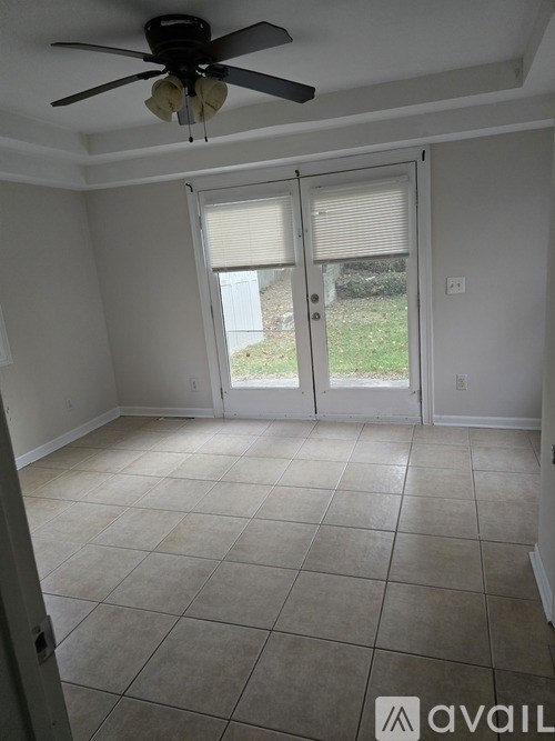 A room with a ceiling fan and sliding glass doors.