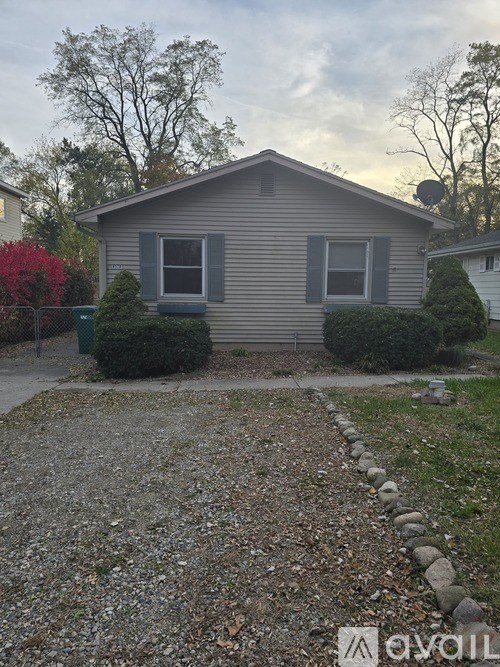 A house with a grey roof and a grey wall with a window and a door.