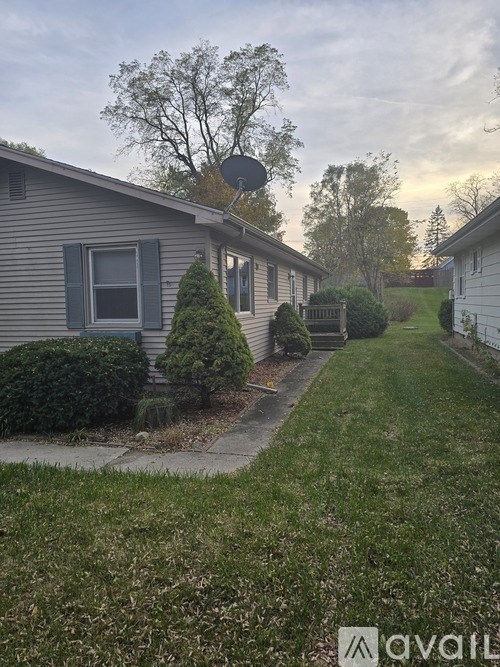 A house with a satellite dish on the roof and a green lawn.